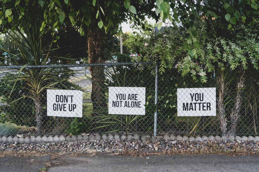 Three signs on a wire fence which say don't give up, you are not alone and you matter